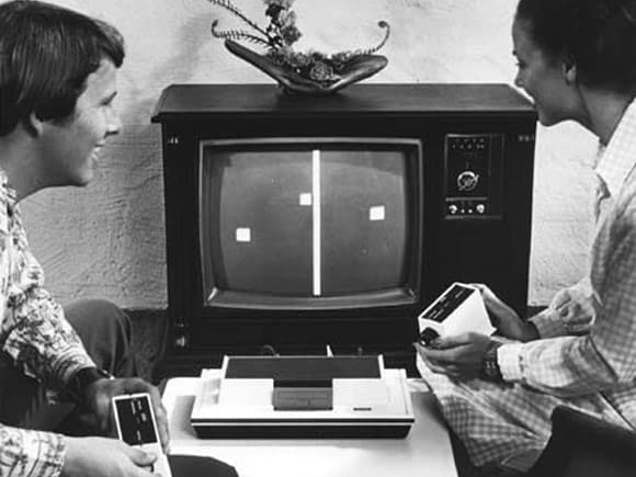 Black and white photograph of two people smiling while playing the Magnavox Odyssey